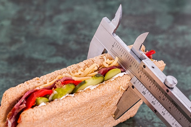 Le sandwich est tranché et garni de concombres, de poivrons rouges, de salami et de fromage râpé.